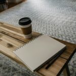 reflective reading in a quiet morning scene with a notebook, pen, and coffee on a simple wooden desk