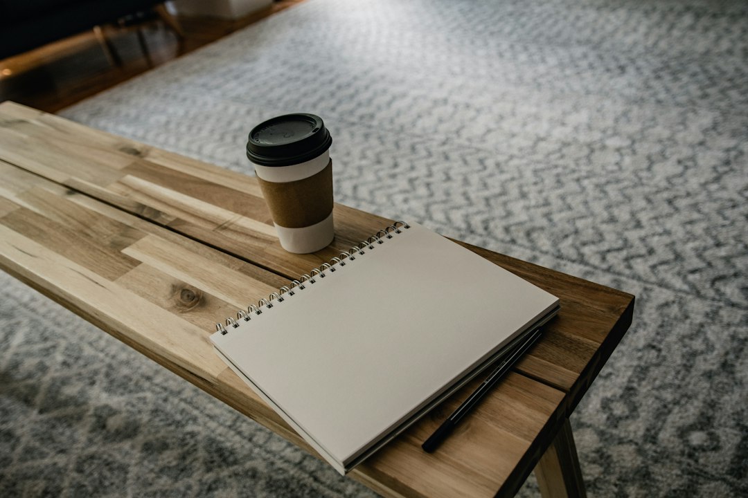 reflective reading in a quiet morning scene with a notebook, pen, and coffee on a simple wooden desk